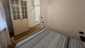 Een slaapkamer met een bed, een garderobe met glazen deuren, een spiegel en een hanglamp.