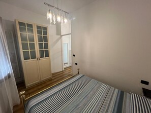 Ein Schlafzimmer mit einem Bett, einem Kleiderschrank mit Glastüren, einem Spiegel und einer Hängeleuchte.