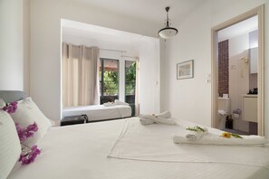 A hotel room with a bed, a bathroom, and a view of greenery outside. - Room 'Double  114' with Shared Terrace, Wi-Fi and Air Conditioning (Nikiana)