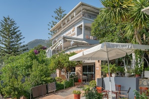 A hotel with outdoor seating, a balcony, and a mountain backdrop. - Room 'Double  114' with Shared Terrace, Wi-Fi and Air Conditioning (Nikiana)