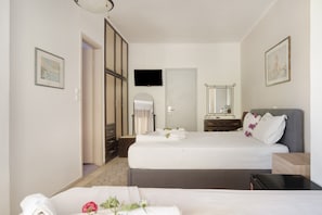 A hotel room with two beds, a TV, a mirror, and a door leading to a bathroom. - Room 'Double  114' with Shared Terrace, Wi-Fi and Air Conditioning (Nikiana)