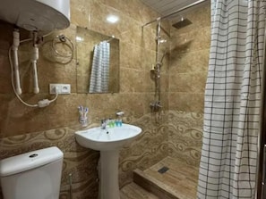 Un baño con lavamanos pedestal, ducha, inodoro y espejo.