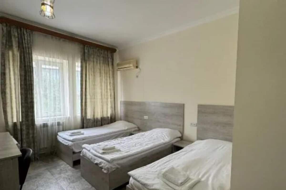 Habitación de hotel con tres camas individuales, un escritorio y una silla.