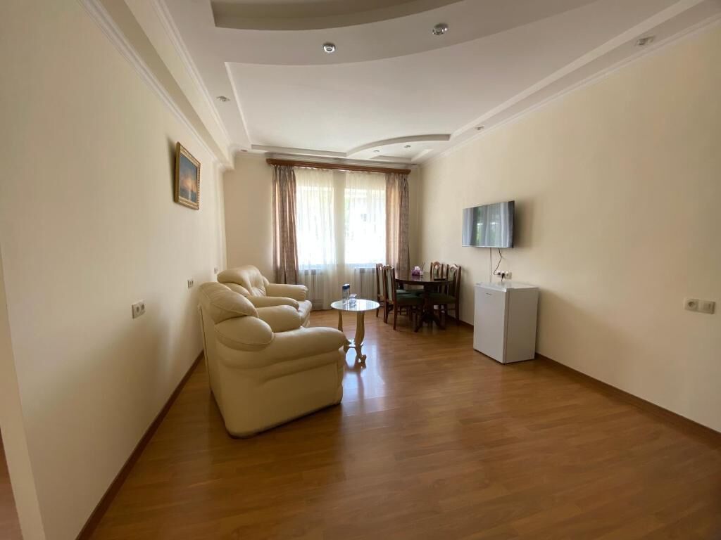 Una sala de estar con un sofá, una mesa de comedor, un televisor y un refrigerador.