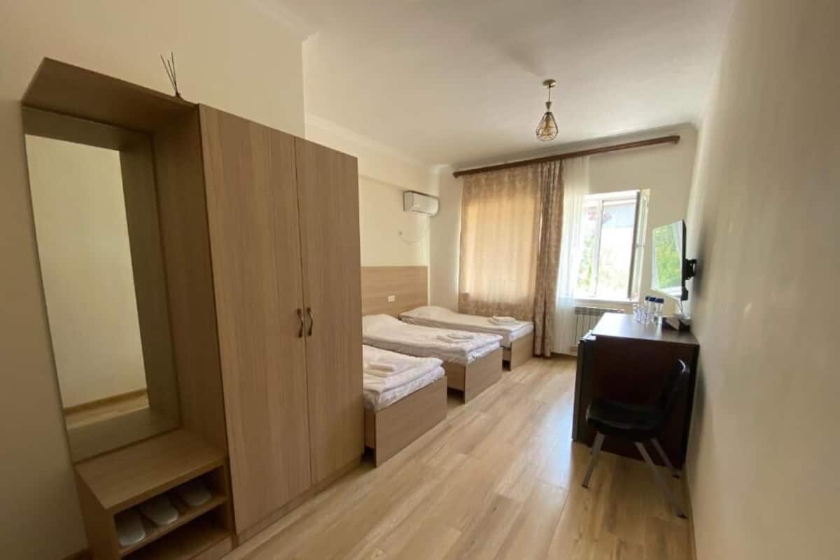 Una habitación con armario, dos camas, escritorio y una silla.