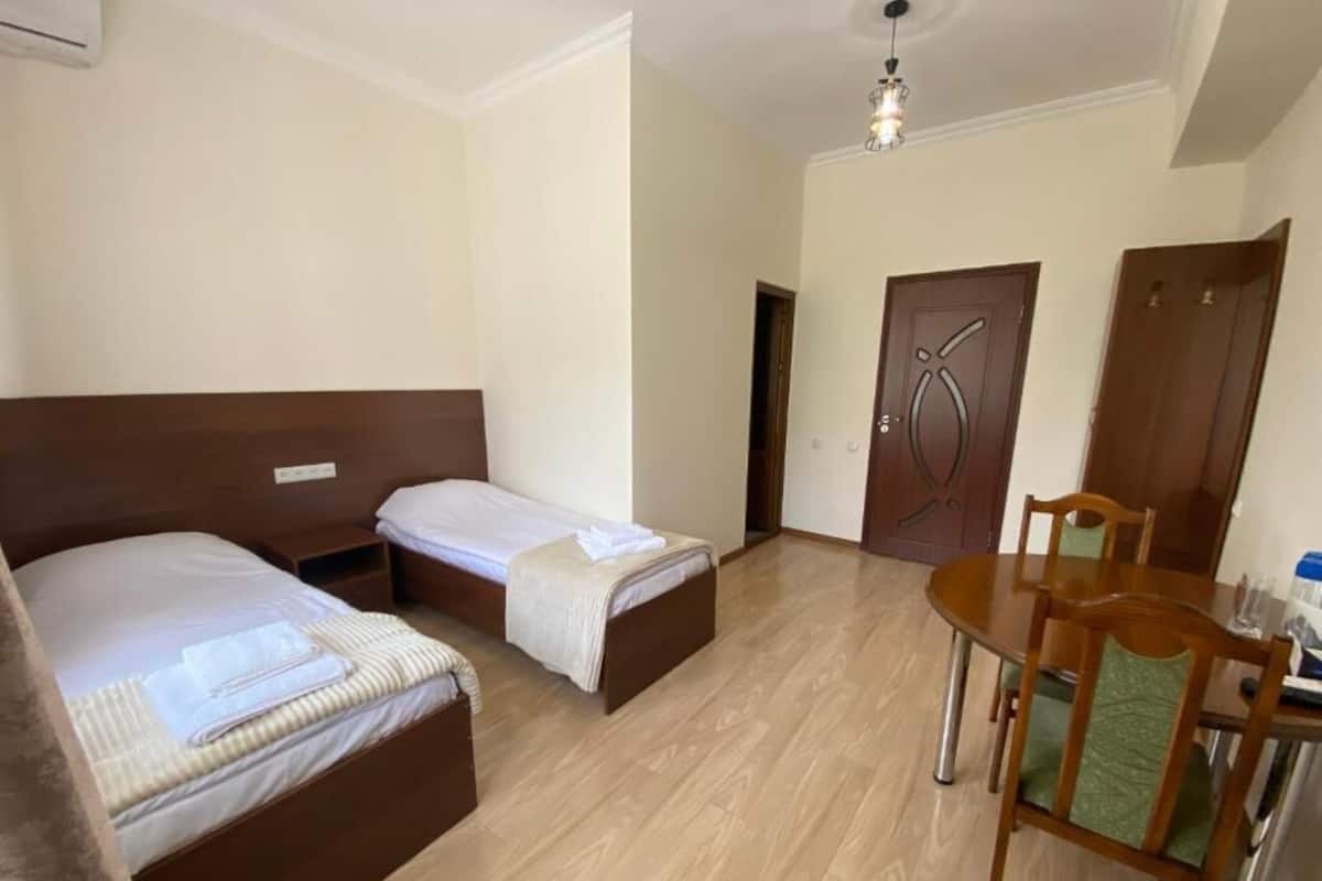 Una habitación de hotel con dos camas, una mesa de comedor y piso de madera.