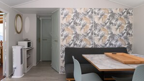 Ein kompakter Wohnraum mit Essbereich, Küchenzeile und einer Tür zu einem weiteren Zimmer.
