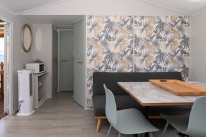 Um espaço compacto com área de refeições, cozinha compacta e uma porta que dá para outro quarto.
