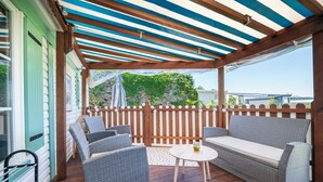 Eine überdachte Terrasse mit Korbmöbeln, einem kleinen runden Tisch und einem Holzzaun.