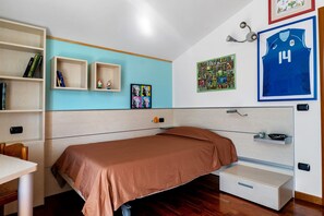 Ein Schlafzimmer mit einem Einzelbett, einem Schreibtisch, Regalen mit Büchern und verschiedenen Wanddekorationen, darunter Sporttrikots.