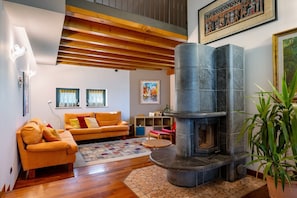 A living room with a fireplace, wooden beams, a sofa, and a potted plant.