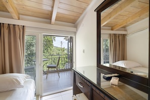 Ein Hotelzimmer mit Balkon, einem Bett, einem Schminktisch, einem Spiegel und einem Fenster.