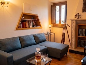 Un salon avec un canapé, une bibliothÚque, un télescope et une cheminée.