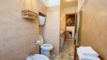 A bathroom with a toilet, bidet, sink, and a towel rack.