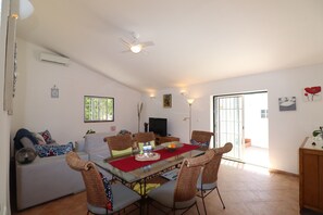 A dining area with a glass table, wicker chairs, a red placemat, and a television in the background. - Casa Susanne Country House with Private Pool, Wi-Fi, and Air Conditioning (Tunes)