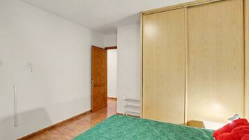 Un dormitorio con cama, armario, puerta y radiador.