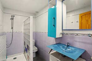 Ein Badezimmer mit Dusche, Toilette und Waschbecken mit blauer Ablagefläche.