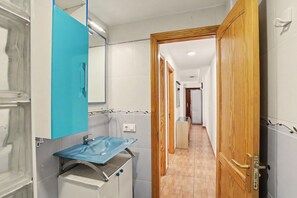 Ein Badezimmer mit einem blauen Waschbecken, einem Spiegel und einer Holztür.
