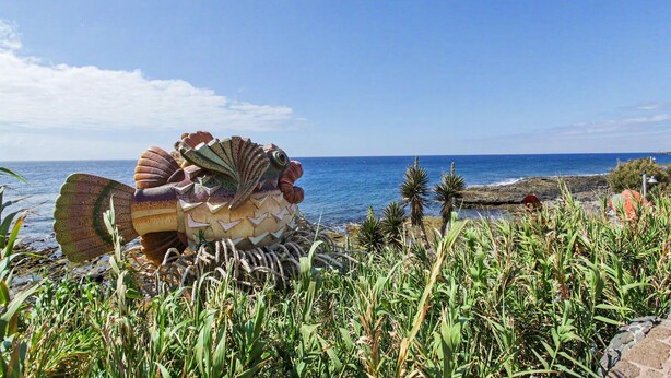 A large sculpture of a sea creature by the ocean.