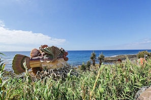 A large sculpture of a sea creature by the ocean.