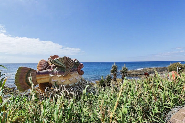 A large sculpture of a sea creature by the ocean.