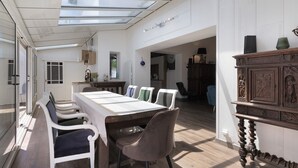 Un vaste espace dédié à la salle à manger, doté d’un plafond haut et de lucarnes, d’une table à manger en bois et de chaises modernes.