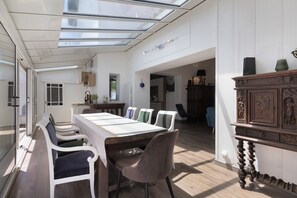Un comedor amplio con techo alto y tragaluces, una mesa de madera y sillas modernas.