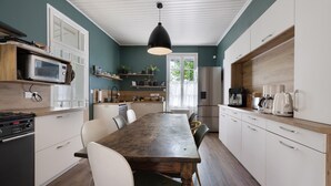 Une cuisine avec une table en bois, des placards blancs, un four à micro-ondes et une machine à café.