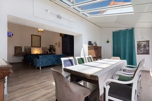 Amplia sala de estar con mesa de comedor, sillas, sofá y tragaluz en el techo.