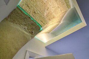 Een kamer met een hoge plafond, een zichtbare hoek en een stuk muur met een structuur.