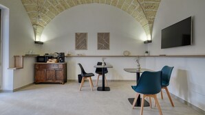 A modern kitchen with a stone ceiling, a flat-screen TV, and a dining area with chairs and a table.