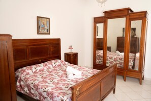 Un dormitorio con cama de madera, una mesita de noche, un espejo y un cuadro en la pared.