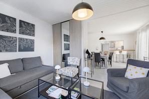 Un salon moderne avec un canapé, des fauteuils, une table basse et des œuvres d’art accrochées aux murs.