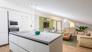 Una cocina moderna con una isla central, un comedor con una mesa y sillas, y una sala de estar con un sofá y una mesita de centro.