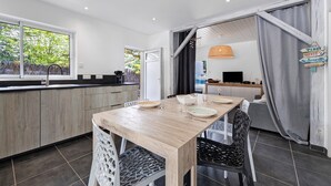 A modern kitchen with a wooden table and chairs, a built-in oven, and a large window.