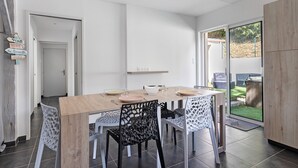 A dining area with a wooden table, chairs, and a view of the backyard through a glass door.