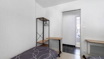 Une chambre à coucher avec un lit, une petite table, une étagère et un radiateur.