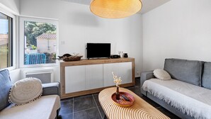 A modern living room with a sofa, a coffee table, a TV, and a large window.