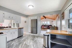A modern kitchen with white cabinets, a stainless steel refrigerator, and a wooden countertop.