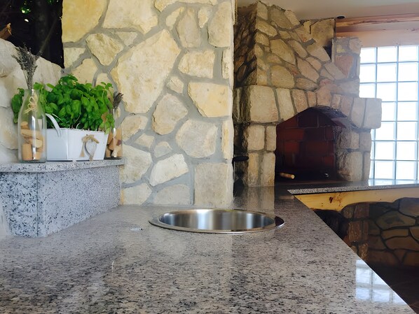 A kitchen with a stone wall, a built-in oven, and a granite countertop.