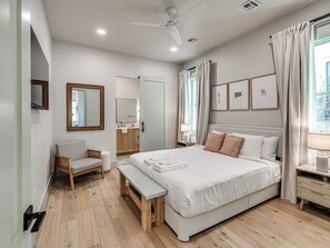 Ein modernes Schlafzimmer mit Bett, Nachttisch, Stuhl und einem großen Fenster mit Vorhängen.