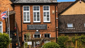 A brick building with a sign for 'The Stag at Lyndhurst Bar | Restaurant | Hotel'. - Charming 2BR Cottage in the Heart of Lyndhurst | Parking & Garden (Lyndhurst)