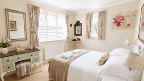 A bedroom with a bed, a dresser, a nightstand, a mirror, and a window with curtains. - Charming 2BR Cottage in the Heart of Lyndhurst | Parking & Garden (Lyndhurst)