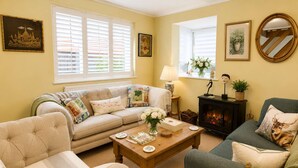 A cozy living room with a sofa, armchairs, a fireplace, and decorative items. - Charming 2BR Cottage in the Heart of Lyndhurst | Parking & Garden (Lyndhurst)