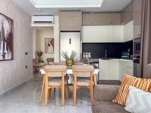 Eine moderne Küche mit eingebauten Geräten, ein Essbereich mit Tisch und Stühlen sowie ein Wohnbereich mit einer Couch.