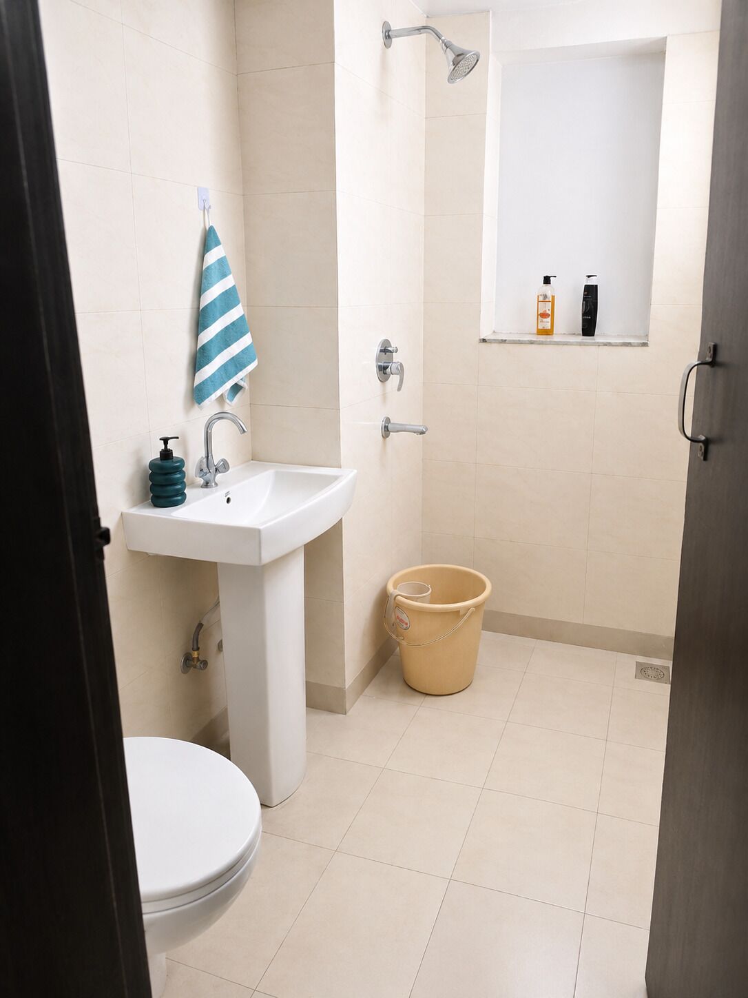 Ein Badezimmer mit Waschbecken, Dusche, Toilette und einem Eimer.