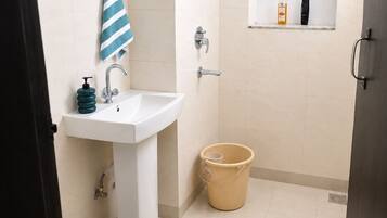 Ein Badezimmer mit Waschbecken, Dusche, Toilette und einem Eimer.