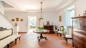 Een ruime kamer met een ronde tafel, een bank, een houten kast en een trap.