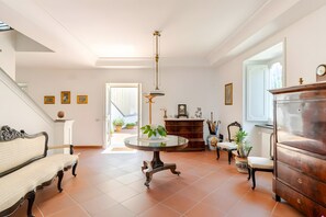 A spacious room with a round table, a sofa, a wooden cabinet, and a staircase. - Holiday Home 'Alexandra' with Sea View, Wi-Fi and Air Conditioning (Vico Equense)