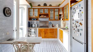 Een keuken met houten kastjes, een koelkast en een eethoek met een tafel en stoelen.